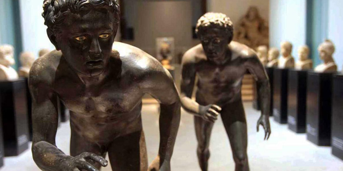 Deux célèbres sculptures en bronze antiques de coureurs exposées dans une salle du MANN.