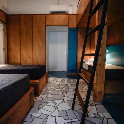 Chambre d’auberge moderne à Naples avec lits simples, mezzanine et décoration contemporaine.