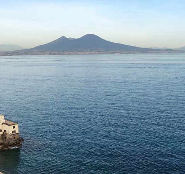 Vue panoramique du golfe de Naples avec le Vésuve en arrière-plan et la côte napolitaine au premier plan.