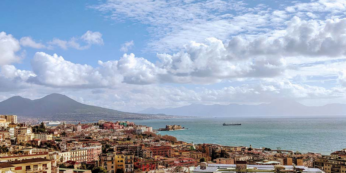 Vue panoramique de Naples avec le Vésuve et le golfe sous un ciel printanier.