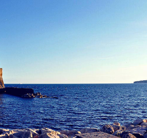 Le Castel dell'Ovo en bord de mer à Naples avec les rochers du littoral au premier plan.