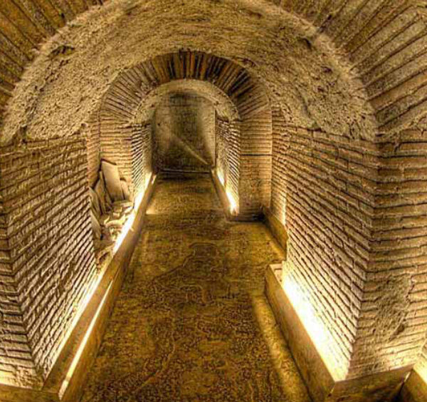 Galerie souterraine de Naples avec couloir en briques éclairé, typique de Napoli Sotterranea.