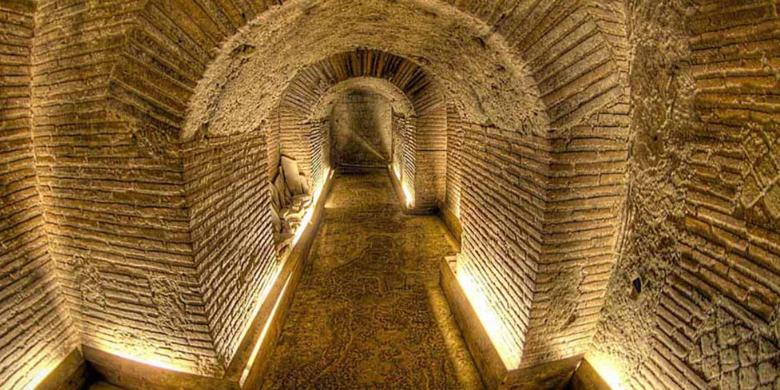 Galerie souterraine de Naples avec couloir en briques éclairé, typique de Napoli Sotterranea.