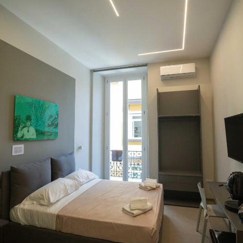 Chambre double moderne avec balcon et décoration minimaliste au centre de Naples.