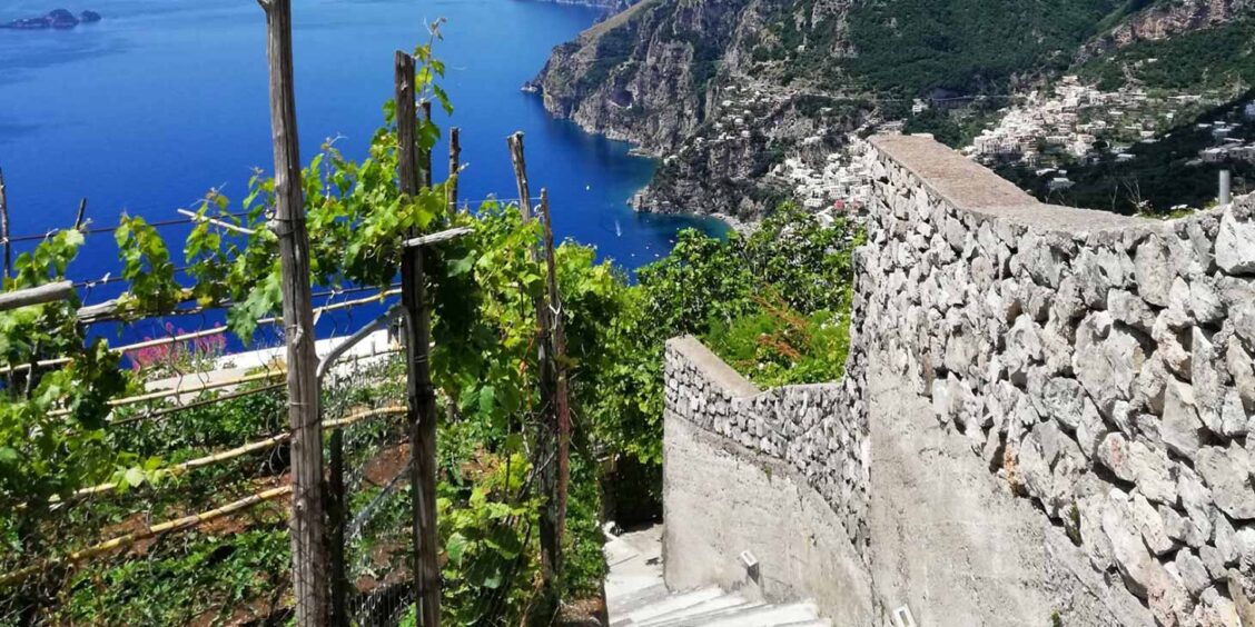 Escaliers en pierre et vignobles à Nocelle avec vue panoramique sur Positano et la Côte Amalfitaine.