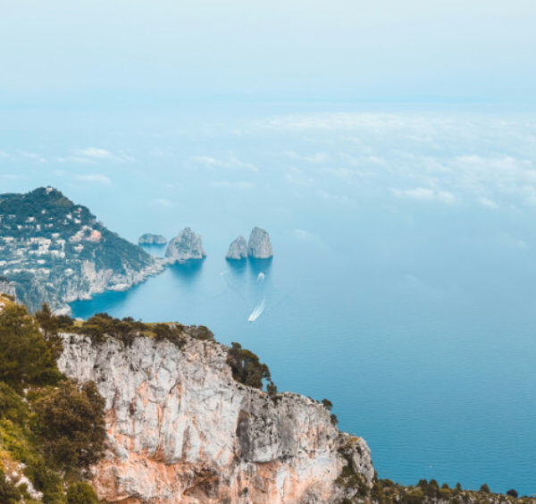 Vue panoramique sur la côte de Capri avec les rochers Faraglioni et une mer légèrement brumeuse en novembre.