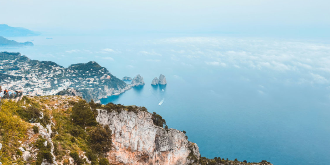 Vue panoramique sur la côte de Capri avec les rochers Faraglioni et une mer légèrement brumeuse en novembre.