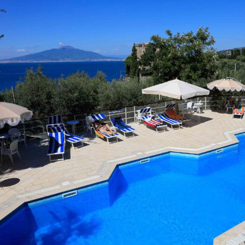 Piscine du Camping Nube d’Argento à Sorrente avec transats et vue sur le Vésuve.