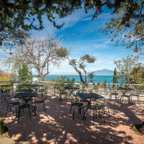 Terrasse panoramique du Camping Nube d’Argento à Sorrente avec tables et vue sur la mer.
