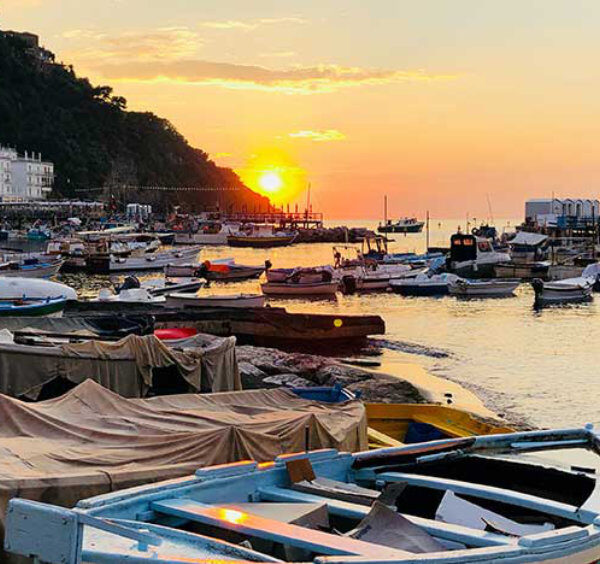 Marina Grande à Sorrente en octobre avec bateaux de pêche et coucher de soleil sur la mer.