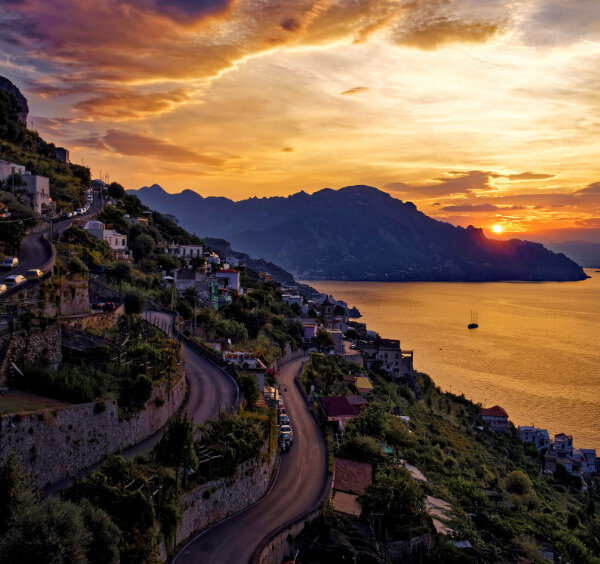 Coucher de soleil doré sur le village de Conca dei Marini et ses routes côtières sinueuses.