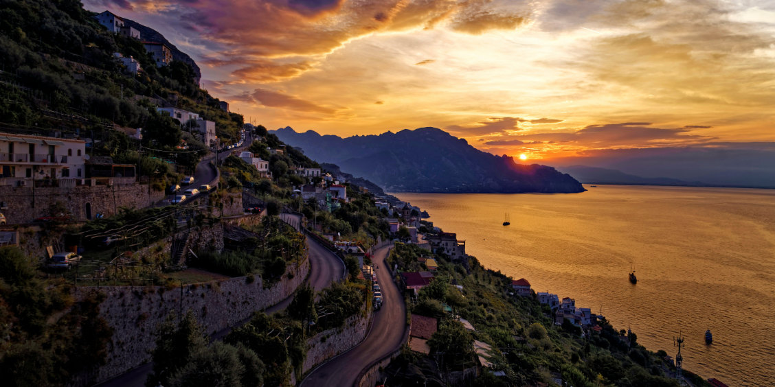 Coucher de soleil doré sur le village de Conca dei Marini et ses routes côtières sinueuses.