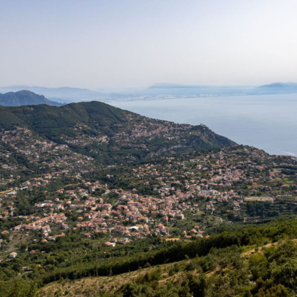 Vue panoramique sur Agerola et la Côte Amalfitaine entre montagnes verdoyantes et mer en arrière-plan.