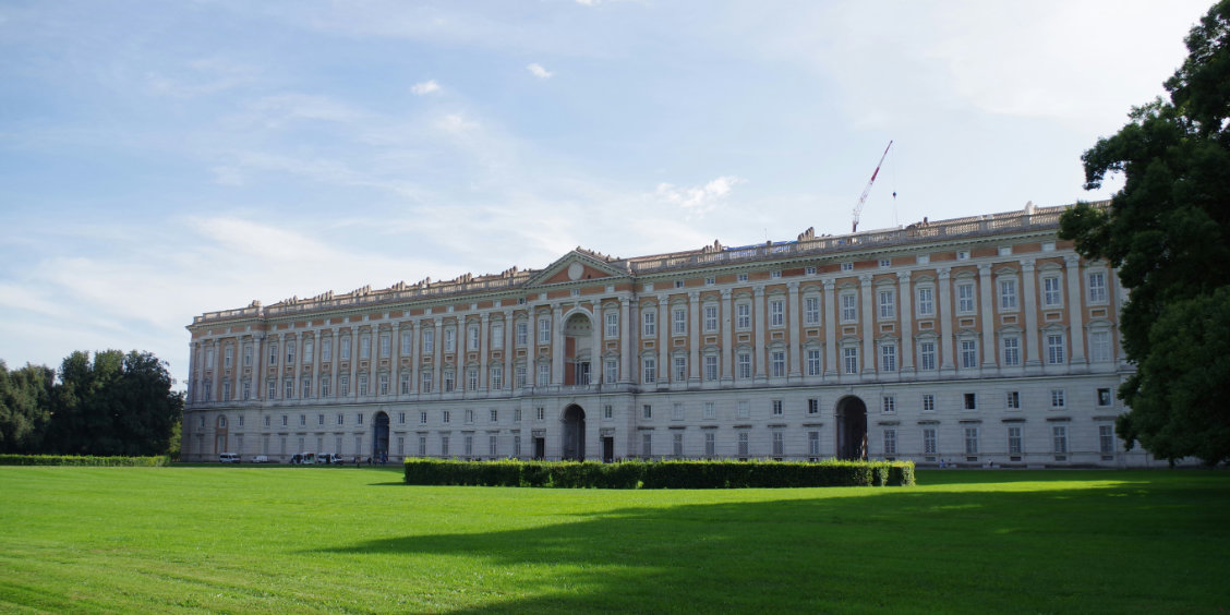 Palais royal de Caserte avec façade monumentale, grande pelouse et jardins.