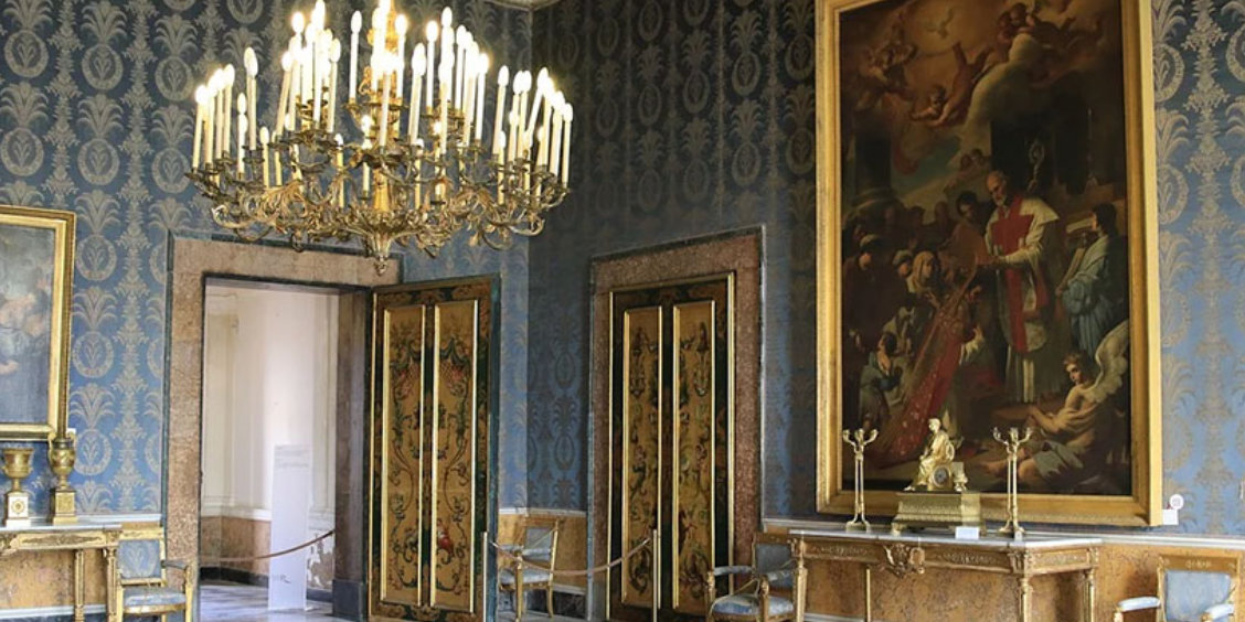 Intérieur du Palais Royal de Naples avec salle richement décorée, lustre et œuvres d’art.