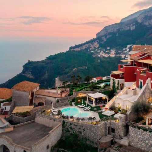 Vue du Palazzo Pascal à Scala avec piscine et panorama côtier au coucher du soleil.