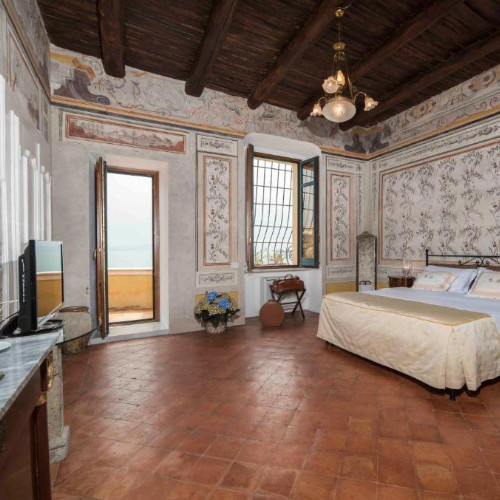 Chambre élégante du Palazzo Suriano avec murs décorés de fresques et poutres apparentes.