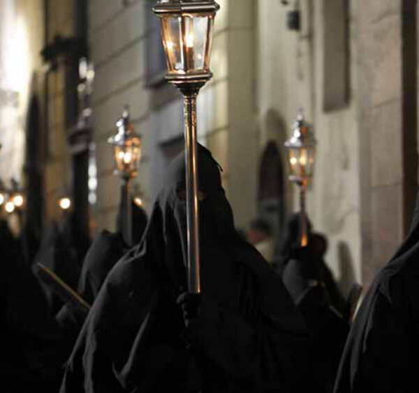 Procession de Pâques à Sorrente avec pénitents en capuchon noir et lanternes allumées.