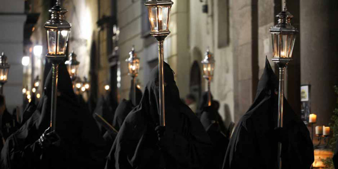 Procession de Pâques à Sorrente avec pénitents en capuchon noir et lanternes allumées.