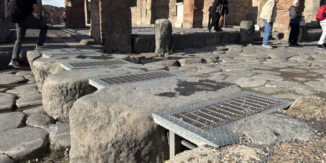 Rampes métalliques installées sur des pierres de passage antiques à Pompéi pour faciliter l'accessibilité.