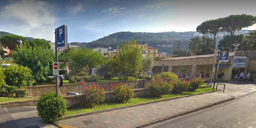 Parking payant à Sorrente avec panneaux, jardin et entrée vers le centre.