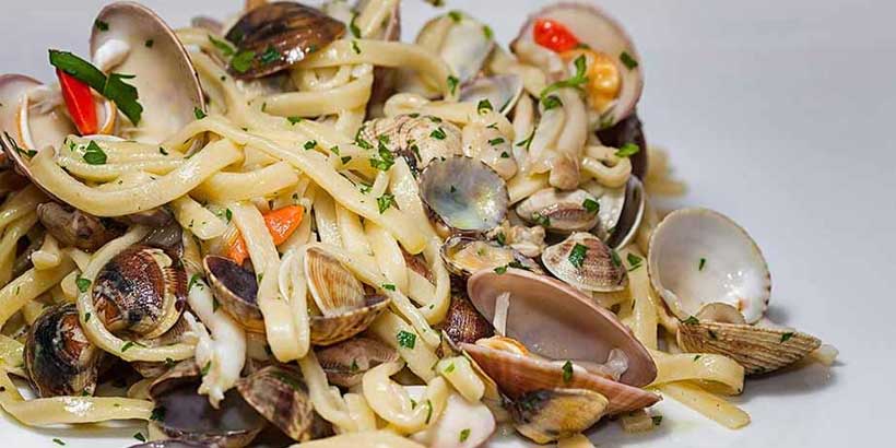 Spaghetti aux palourdes typiques de Naples avec fruits de mer et persil frais.