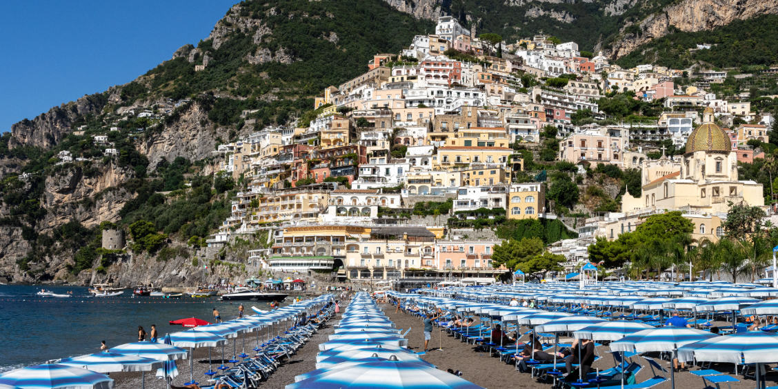 Rangées de transats et parasols bleus sur la plage de Positano pour la baignade.
