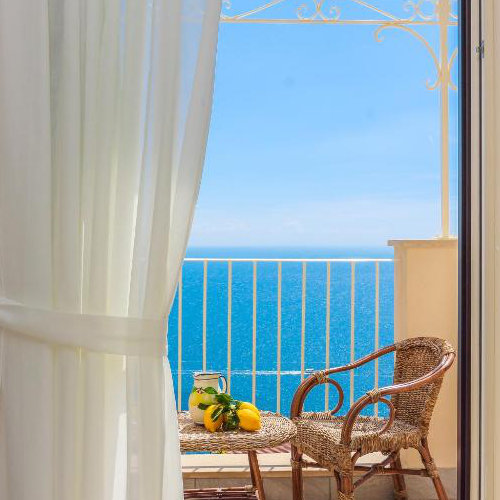 Balcon du Pesce d’Oro à Amalfi avec table, chaise et vue sur la mer.