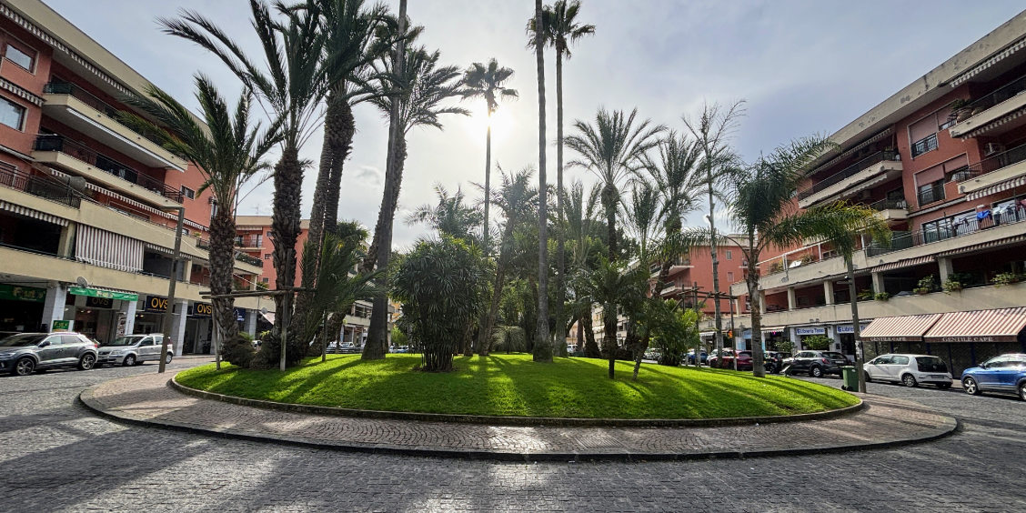 Piazza Lauro à Sorrente avec palmiers et jardin central ensoleillé.