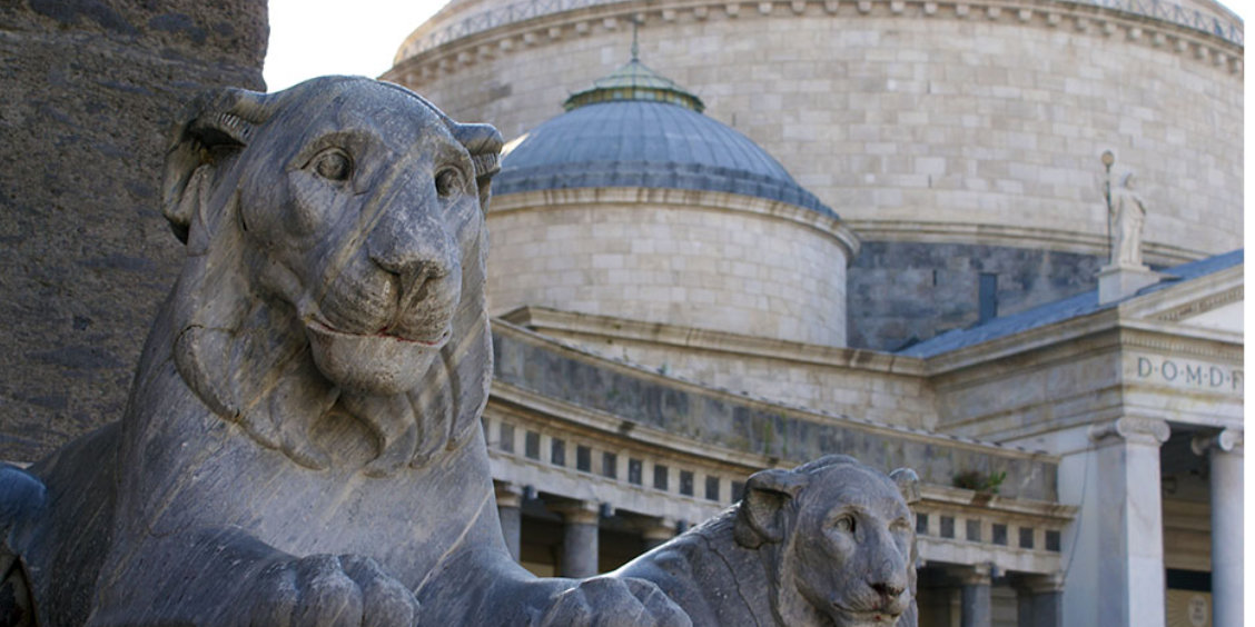 Statues de lions sur la place du Plébiscite avec la basilique en arrière-plan à Naples.