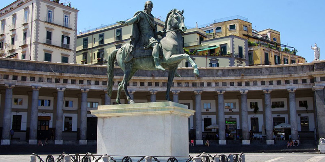 Place du Plebiscito à Naples avec statue équestre et colonnade monumentale.