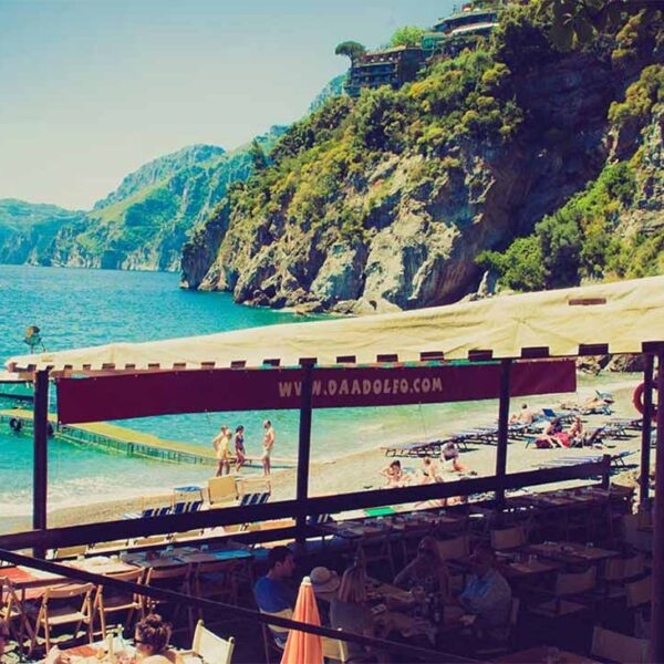 Plage de Laurito à Positano avec restaurant en bord de mer et falaises de la Côte Amalfitaine.