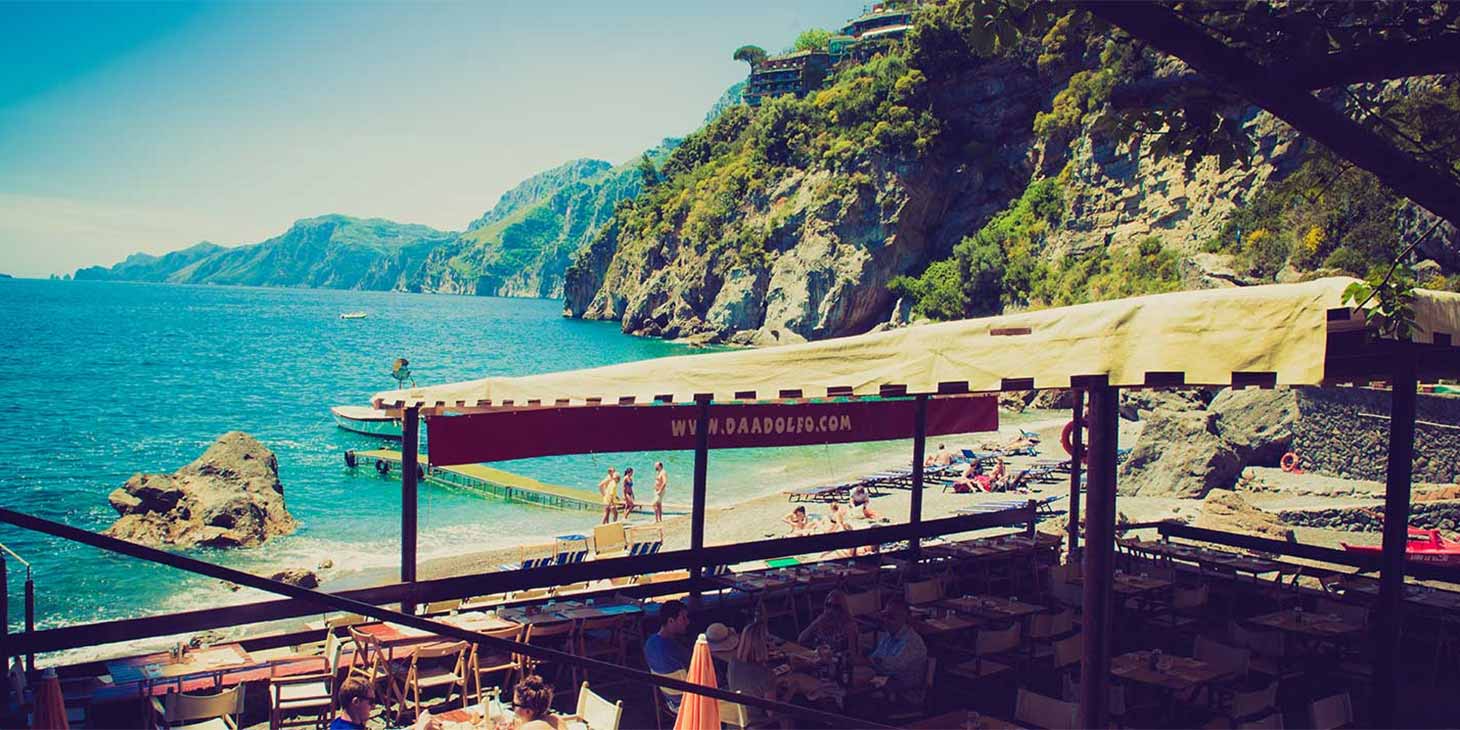 Plage de Laurito à Positano avec restaurant en bord de mer et falaises de la Côte Amalfitaine.