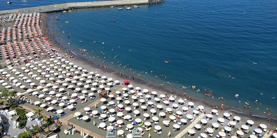 Plage de Sorrente en septembre avec parasols, baigneurs et mer bleue.