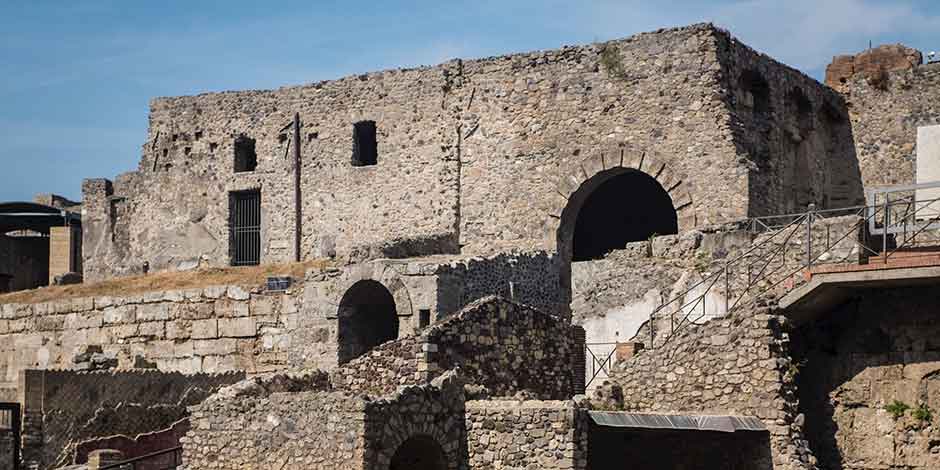 Détail des murs en pierre et des arches des ruines antiques de Pompéi sous un ciel dégagé.