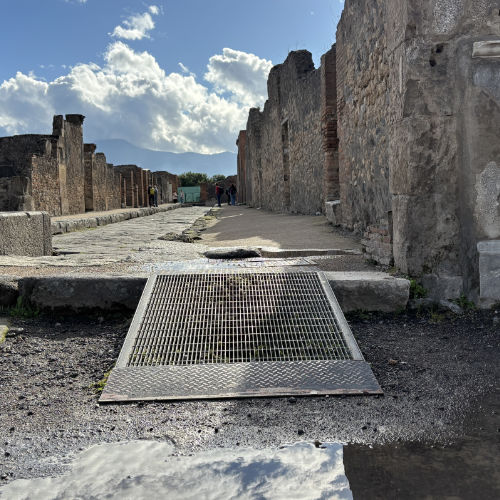 Rampe métallique installée sur une rue pavée de Pompéi pour faciliter l'accessibilité.
