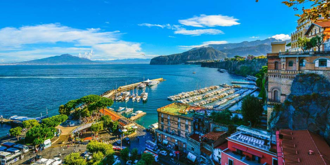 Port de Sorrente avec bateaux, falaises et vue sur le Vésuve dans le golfe de Naples.