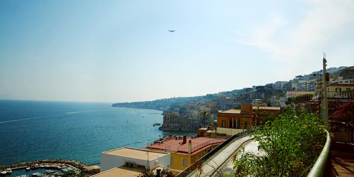 Le port de Mergellina à Naples avec des bateaux et la colline de Posillipo en arrière-plan.
