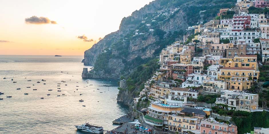 Positano au coucher du soleil en août avec maisons colorées et bateaux sur la mer.