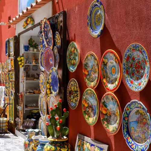 Boutique de céramiques colorées exposées sur un mur ensoleillé de la Côte Amalfitaine.