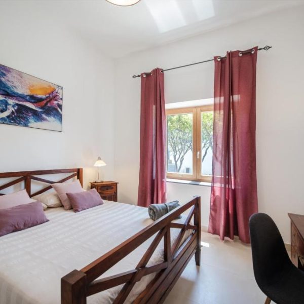 Chambre lumineuse avec lit en bois au B&B Prochytea à Procida, idéal pour un séjour détente en Campanie.