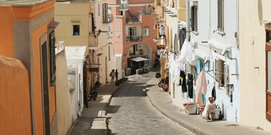 Ruelle sinueuse en pente de Procida, Campanie, bordée de maisons colorées et de linge suspendu.