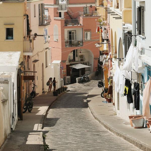 Ruelle sinueuse en pente de Procida, Campanie, bordée de maisons colorées et de linge suspendu.