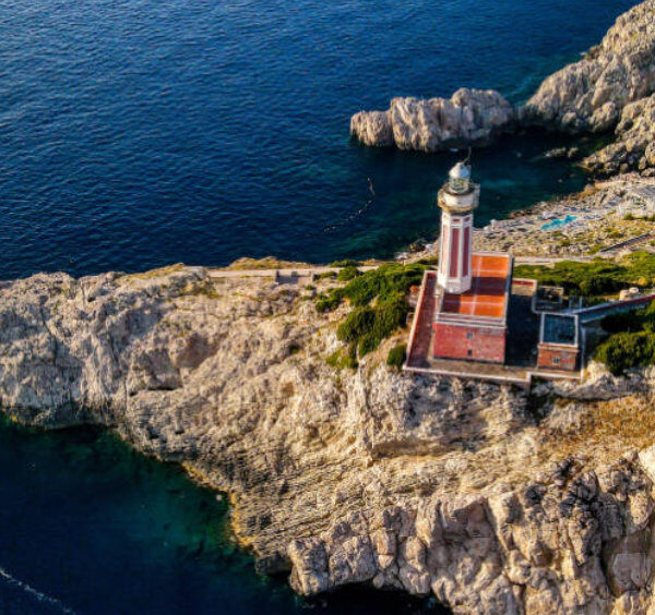 Vue aérienne du phare rouge de Punta Carena à Capri sur son promontoire rocheux dominant les eaux bleues azur.