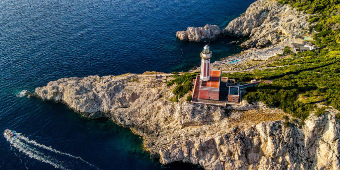 Vue aérienne du phare rouge de Punta Carena à Capri sur son promontoire rocheux dominant les eaux bleues azur.