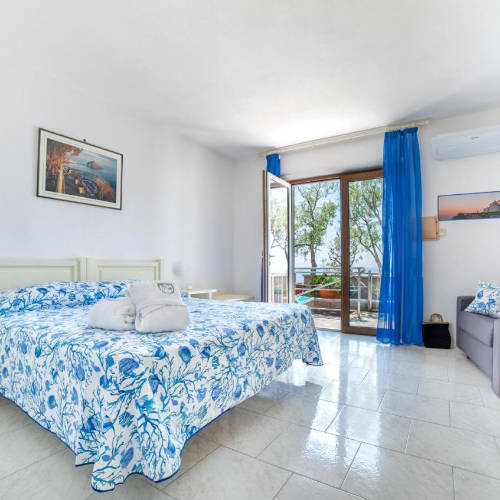 Chambre spacieuse et lumineuse avec décoration d'inspiration marine et balcon à l'hôtel Punta Chiarito.