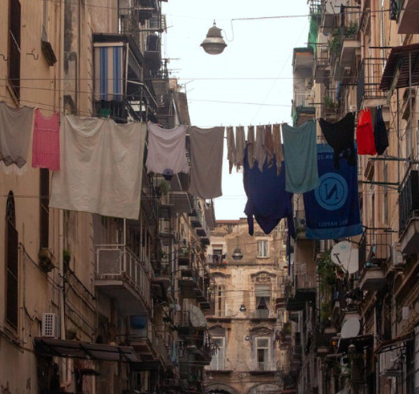 Ruelle étroite et authentique du quartier Materdei à Naples, avec du linge séchant sur des fils entre les bâtiments.