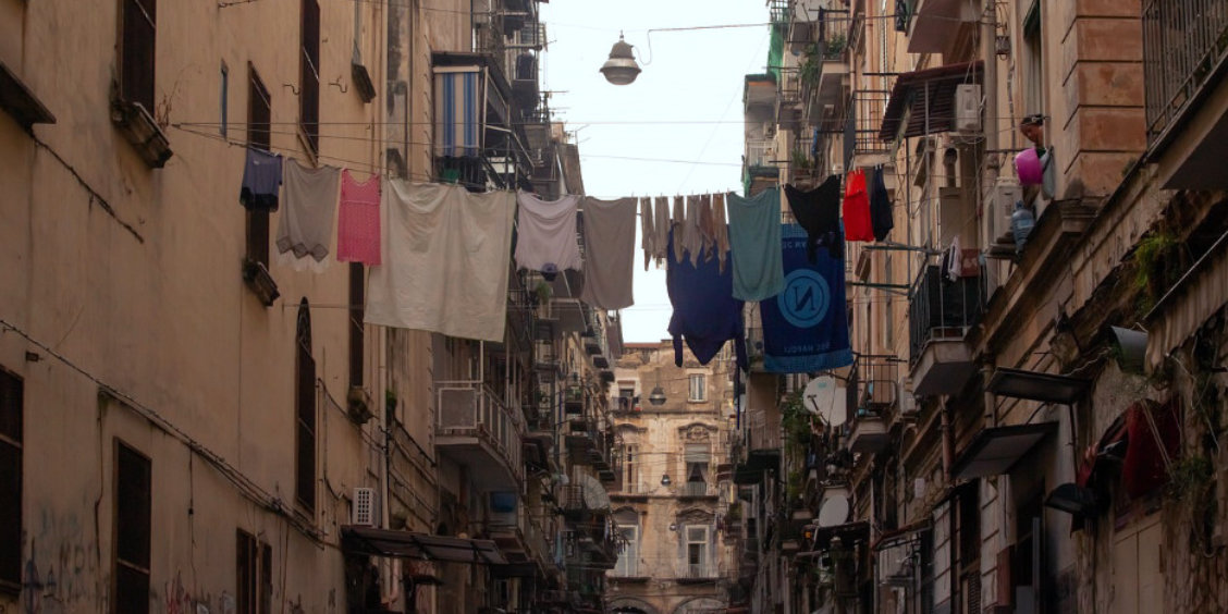 Ruelle étroite et authentique du quartier Materdei à Naples, avec du linge séchant sur des fils entre les bâtiments.