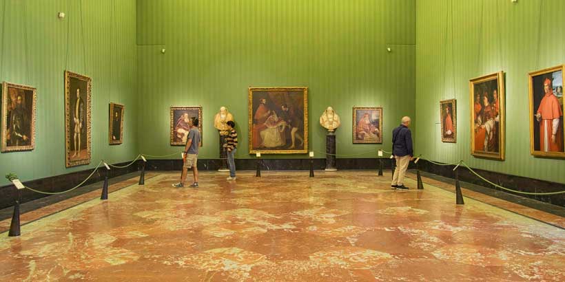 Visiteurs admirant les chefs-d'œuvre de la collection Farnèse dans une salle aux murs verts du musée national de Capodimonte à Naples.