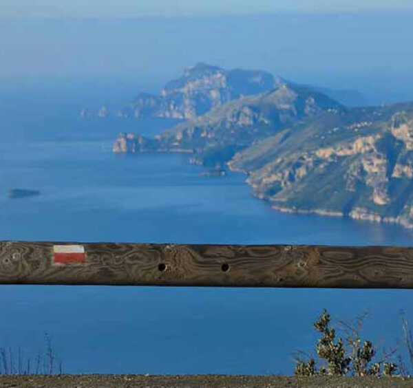 Vue panoramique de randonnée près de Sorrente avec mer bleue, falaises et côte au loin.